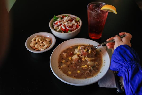 Table with a bowl of soup, crackers, salad, and beverage with a lemon