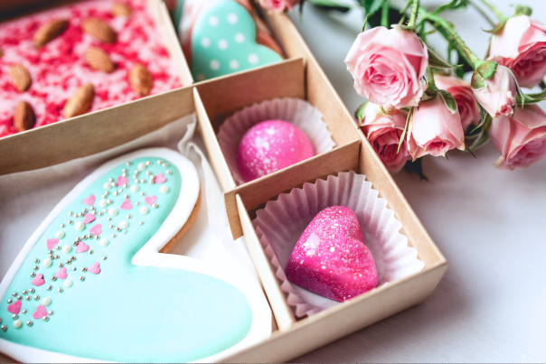 Picture of box of treats next to 6 pink roses