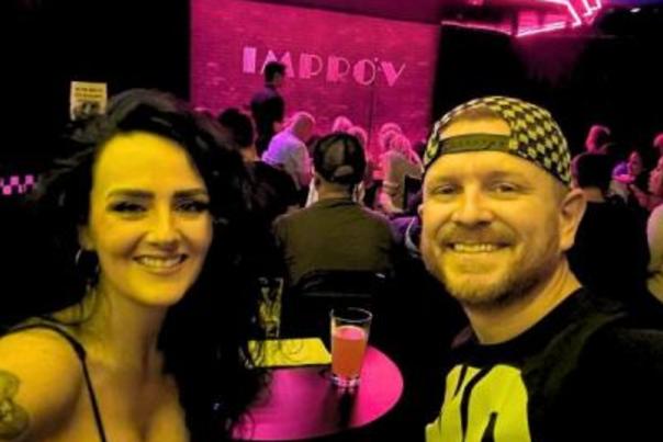 Two people sitting at a table in front of the improv stage.