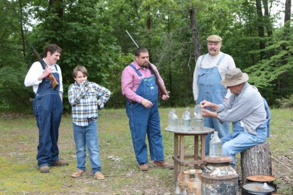 A man showing four other gentlemen how moonshine is made on the mountain.