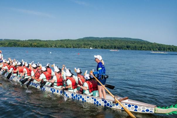 A team of 20 rowers, a drummer and a steerer race a 46-foot-long traditional dragon boat across the water.
