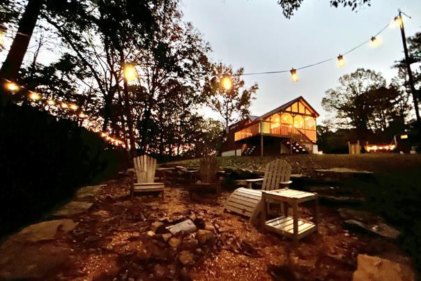 Fire Tower Camp cabin and chairs with string lights at dusk.