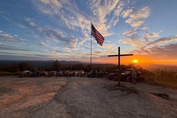 atvs lined up at the overlook with a beautiful sunset, cross, and flag at indian mountain atv park