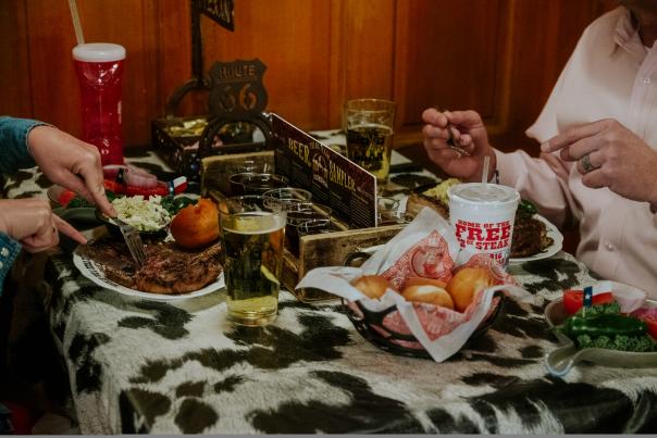 Photo of a couple enjoying steak, beer, and dinner rolls at the Big Texan in Amarillo, Texas