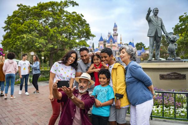 Image of a family in front of the castle at Disneyland Resort. The family is gathered together to take a selfie.