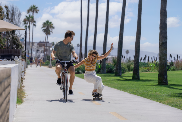 Couple biking and skating in Newport Beach Boardwalk during Labor Day