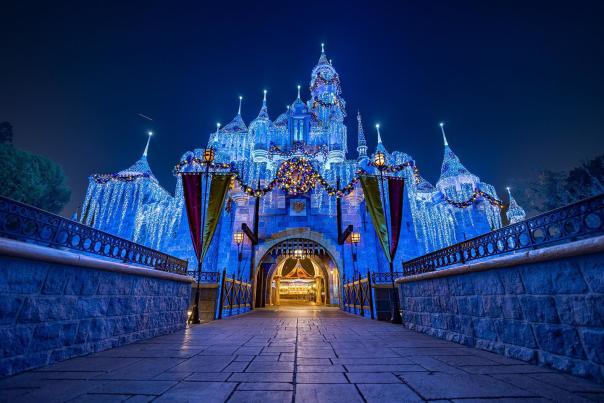 Image of Sleeping Beauty's Castle at Disneyland light up at night. Ice and snow can be seen adorning the castle.