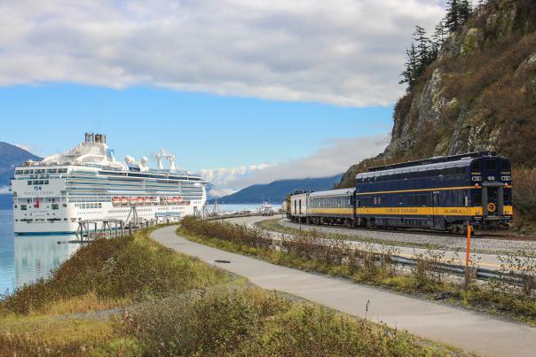 The Glacier Discovery train pulls into Whittier with a docked cruise ship