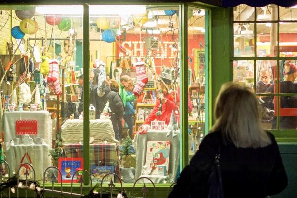 Woman looks into window and people shop inside