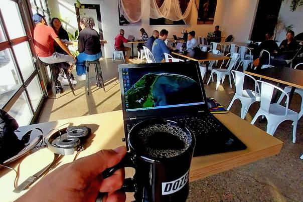 first-person perspective of sitting at a table with a laptop set up and coffee in-hand.