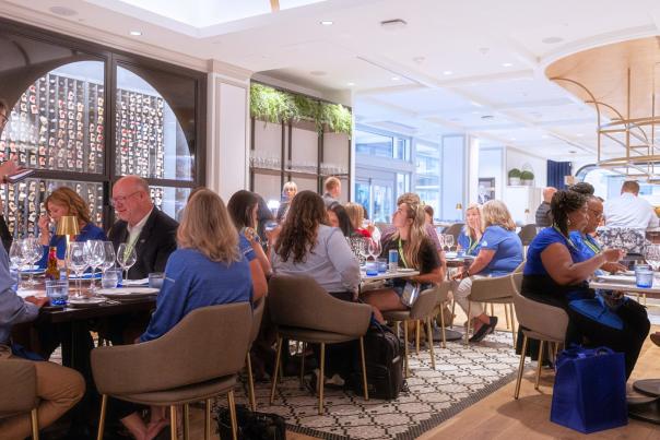large group of people dine inside of a restaurant with elegant design covering the walls.