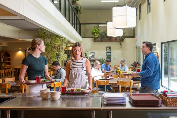 Image of people in a cafeteria-style line picking up their trays of food to take to the table.
