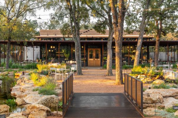 Photo of the outside of Leona with green landscaping and a small bridge out front.