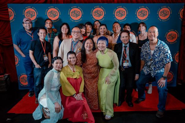 Film festival goers standing in front of a step and repeat sign at Austin Asian American Film Festival.