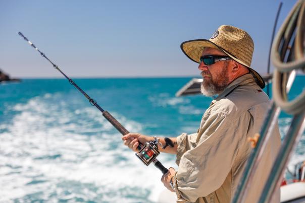 A man holding a fishing rod on a boat, taken in the Dampier Archipelago near Karratha in the Pilbara