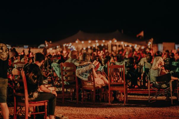 People gathered at the evening entertainment at the Karijini Experience, sitting on chairs and with strings of lights