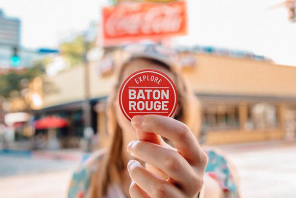 Woman Holding Baton Rouge Sticker In front Of Her Face