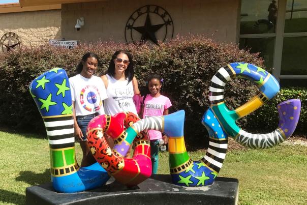 Woman and her two daughters standing in behind a LOVE sign