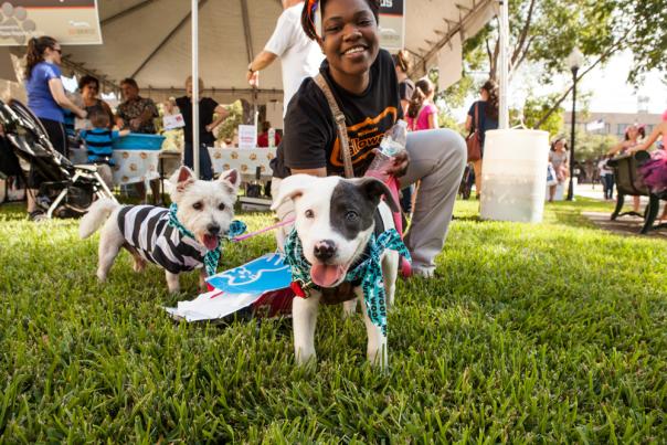 Women kneeling on grass posing with puppies at Dogtober Fest