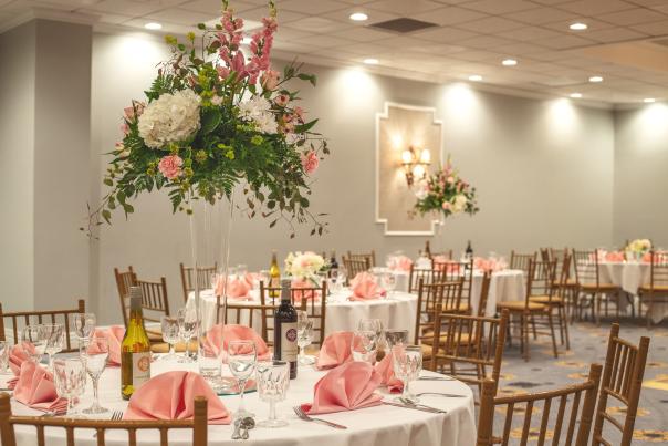 Ballroom set up with pink and white decor and flower center pieces at the MCM Elegante Beaumont