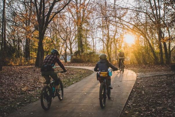 Three individual riding a paved trail at sunset