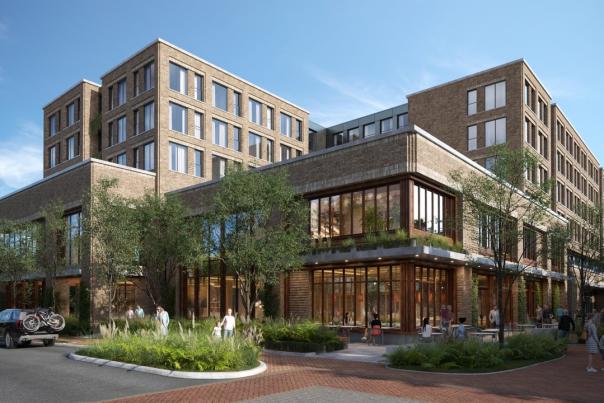 A daytime, eye-level rendering showcases a modern, multi-story brick building situated at the corner of a city street. The building features large glass windows on the lower levels, suggesting retail or restaurant spaces, with people visible both inside and outside. Above, multiple floors with smaller, regularly spaced windows indicate residential or office units. Trees and landscaping surround the base of the building, softening its urban presence. A dark SUV with bicycles mounted on the back is parked along the street in front of the building. Pedestrians stroll along the sidewalks and gather at outdoor tables in front of the ground-floor businesses. The street is paved, and the sky above is clear and blue.