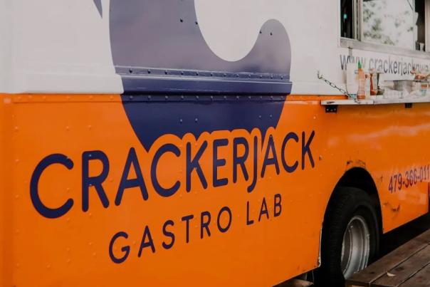 The exterior of Crackerjack Gastro Lab food truck is orange on the bottom half and white on the top half.