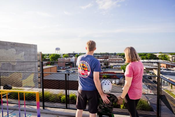 Family overlooking Bentonville's town center from a rooftop, showcasing urban landscape and community vibe.