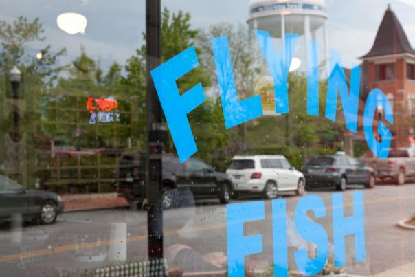 Sticker that reads "flying fish" in blue ink on the window of the restaurant.