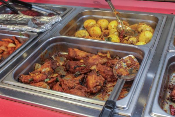 A metal serving tray displays flavorful chicken pieces and seasoned potatoes, inviting culinary exploration. The vibrant food setup suggests a lively dining experience.