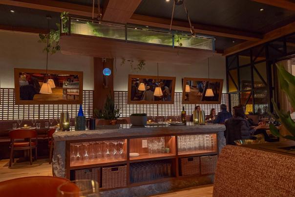 Warm restaurant interior with wood accents, stone, and greenery.