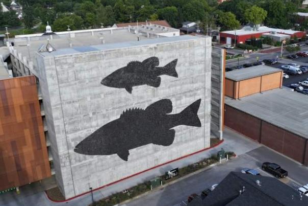 Large fish mural on the side of a Bentonville parking structure, showcasing the town's public art installations, visible from nearby group tour routes.