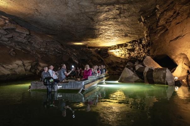 A group of people on a boat looking up at the ceiling of a cave on a underground river boat tour at Lost River Cave in Bowling Green, KY.