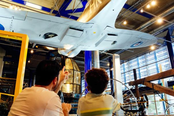 A father and son look up at the underside of a WWII plane in the ThinkTank in Birmingham
