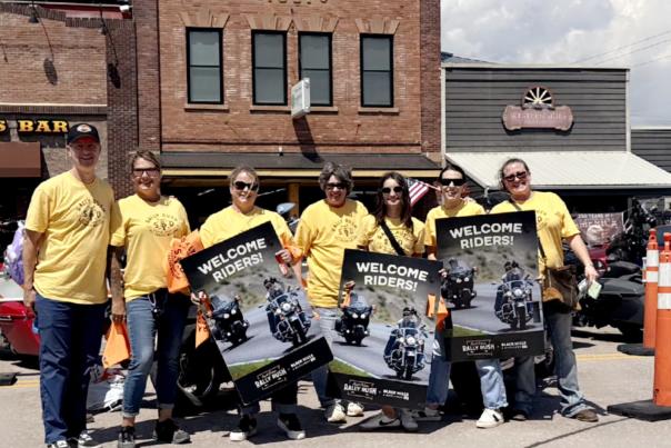 BH&B staff holding "Welcome Riders" signs at Rally Rush