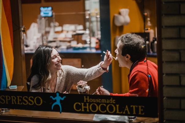 A woman feeding a man a spoonful of ice cream at Blu Boy