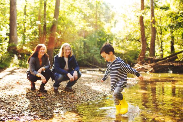 A lesbian couple watching their son play in a creek