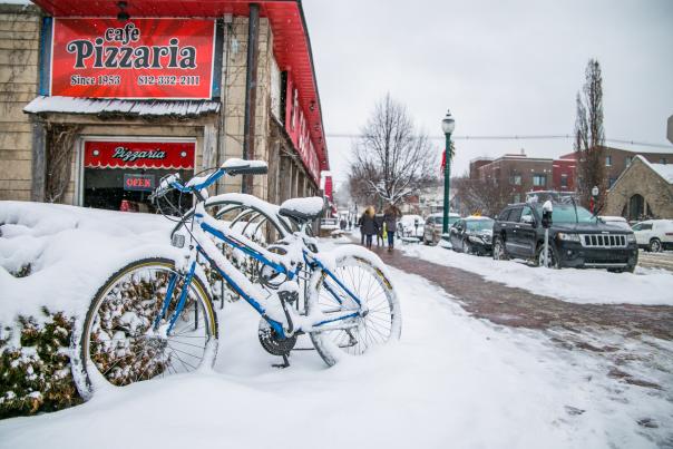 A bike covered in snow on Kirkwood Avenue in front of Cafe Pizzaria