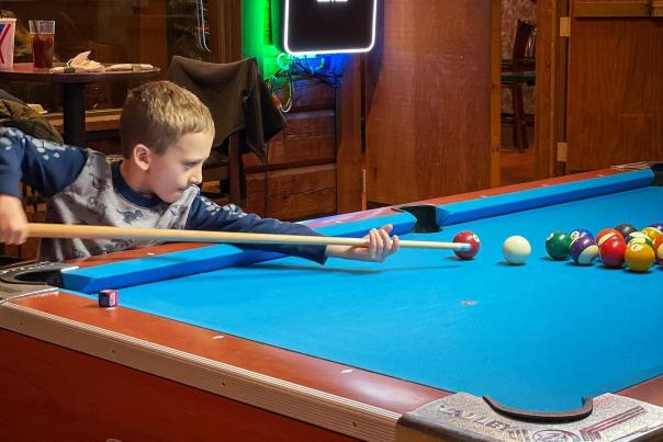 A young boy playing pool at IMU Bowling & Billiards