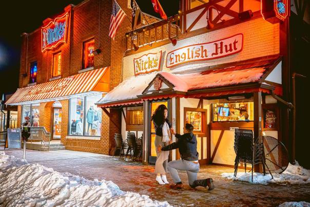 A man proposing to a woman in front of Nick's English Hut