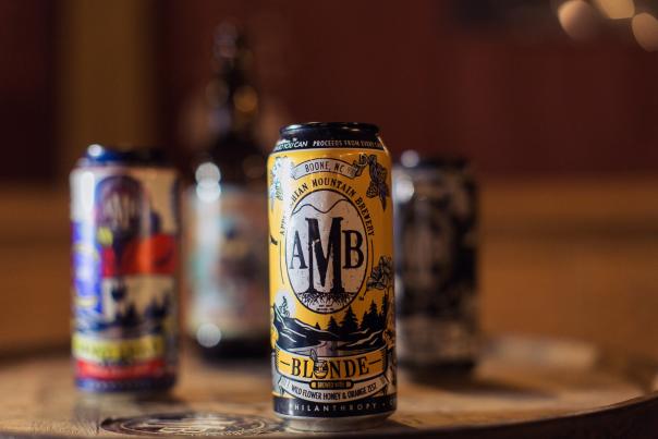 Several cans and a growler sit on a table at Appalachian Mountain Brewery.