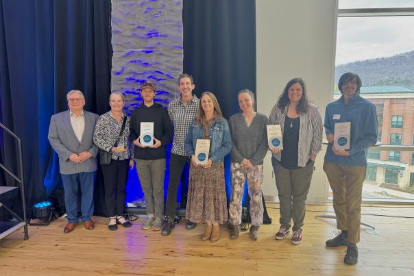 At the 2024 Annual Partners' Meeting, local tourism partners are shown holding their awards.