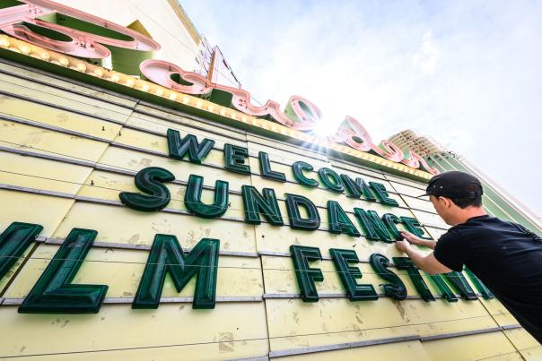 A man sets up letters on the Boulder Theater marquee that read "Welcome Sundance Film Festival"
