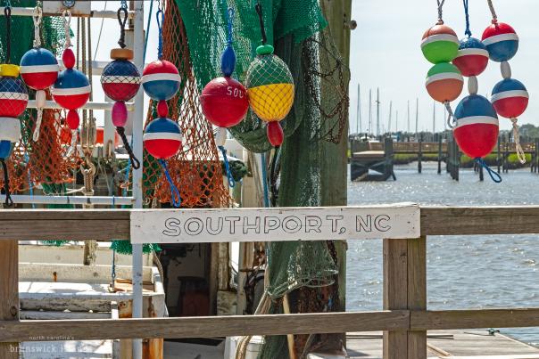 a wooden sign reading Southport, NC on a railing overlooking a body of water