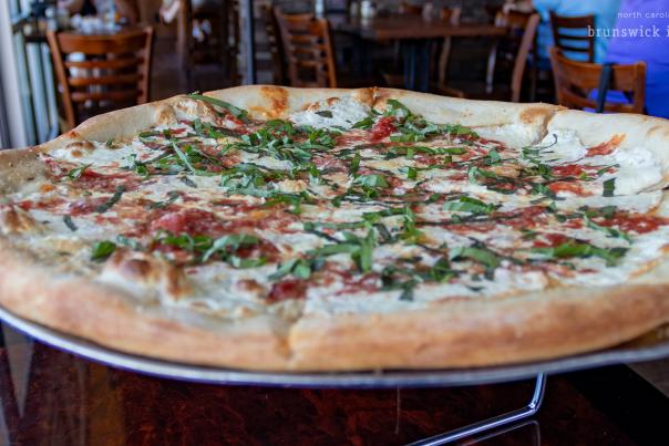 a closeup photo of a pizza topped with chopped basil, cheese, and tomato sauce