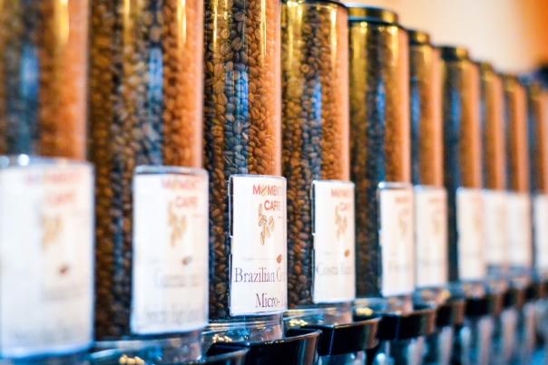 a view of 10 clear containers filled with Momentto Coffee Roaster's roasted coffee beans as displayed at their Chandler, AZ coffee shop