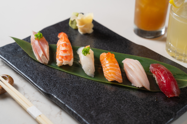 Five different nigiri sushi options beautifully plated on a black plate.
