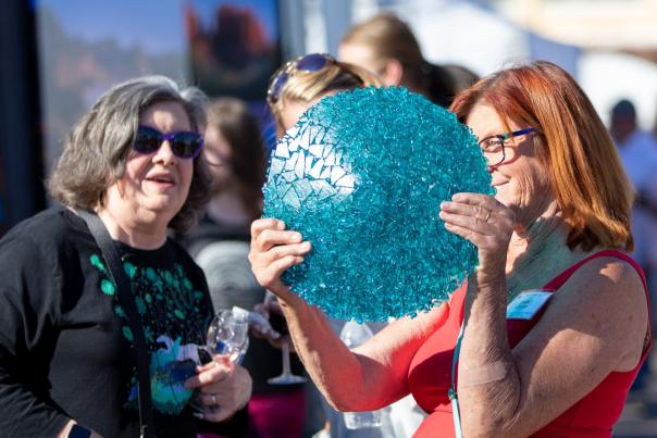 two ladies admiring a glass plate at an outdoor festival