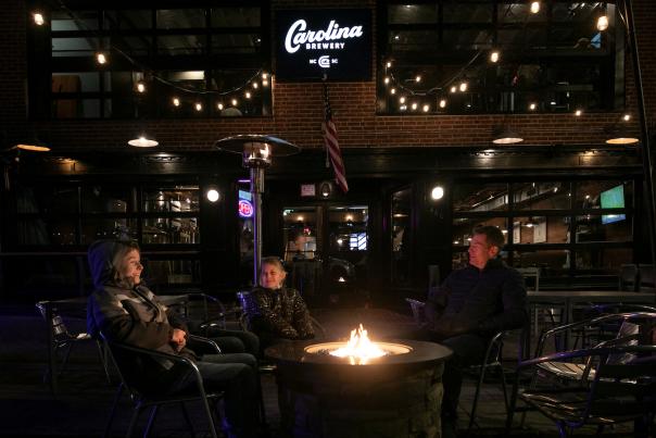 People sitting around a firepit on the outdoor patio at Carolina Brewery
