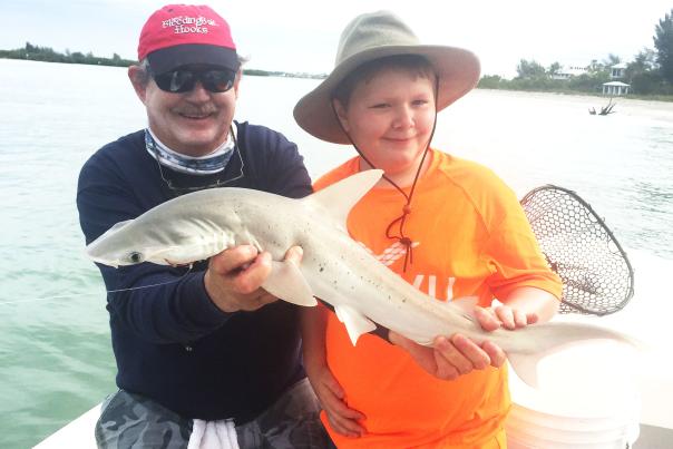 Fishing: Capt. Van Hubbard and a child hold a shark